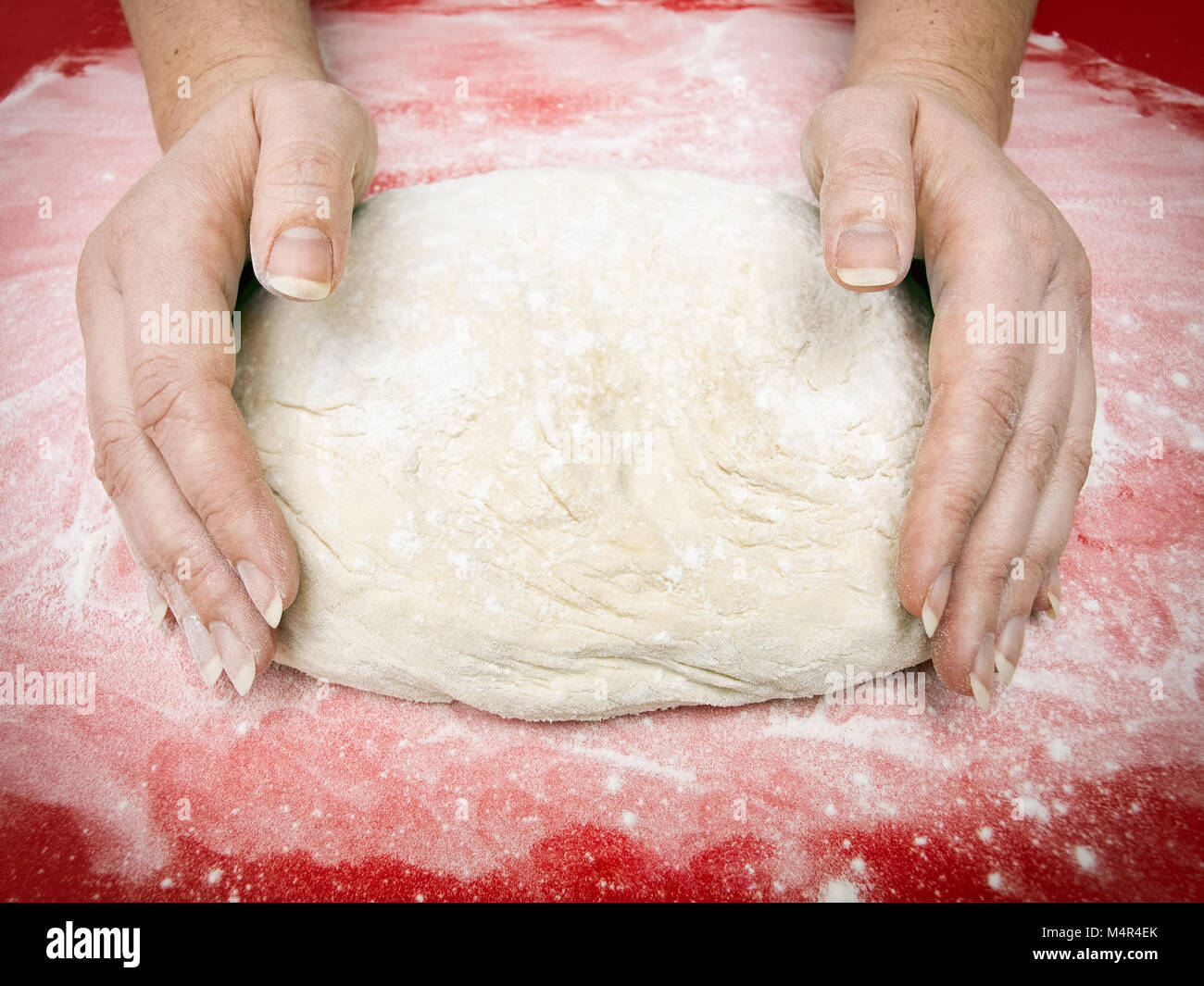 Woman is making a dough on a red background. Stock Photo