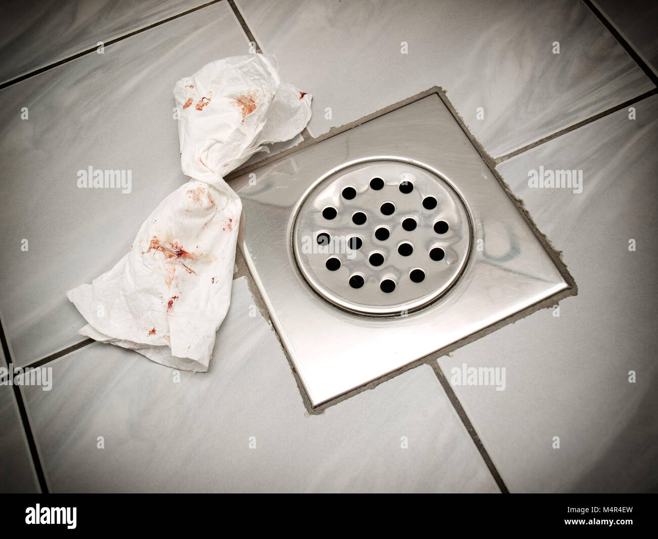 Bloody paper tissue on the floor of a bathroom or toilette. Stock Photo