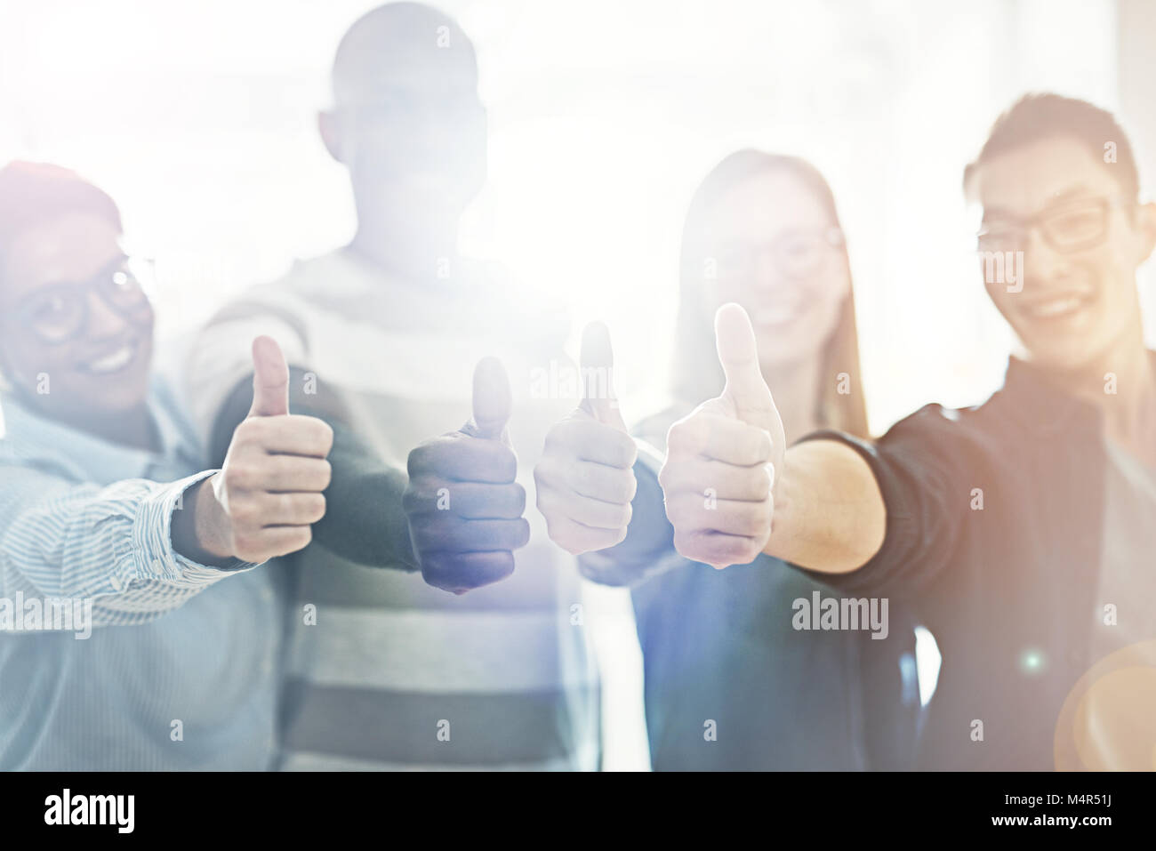 Smiling group of diverse business colleagues giving the thumbs up while ...