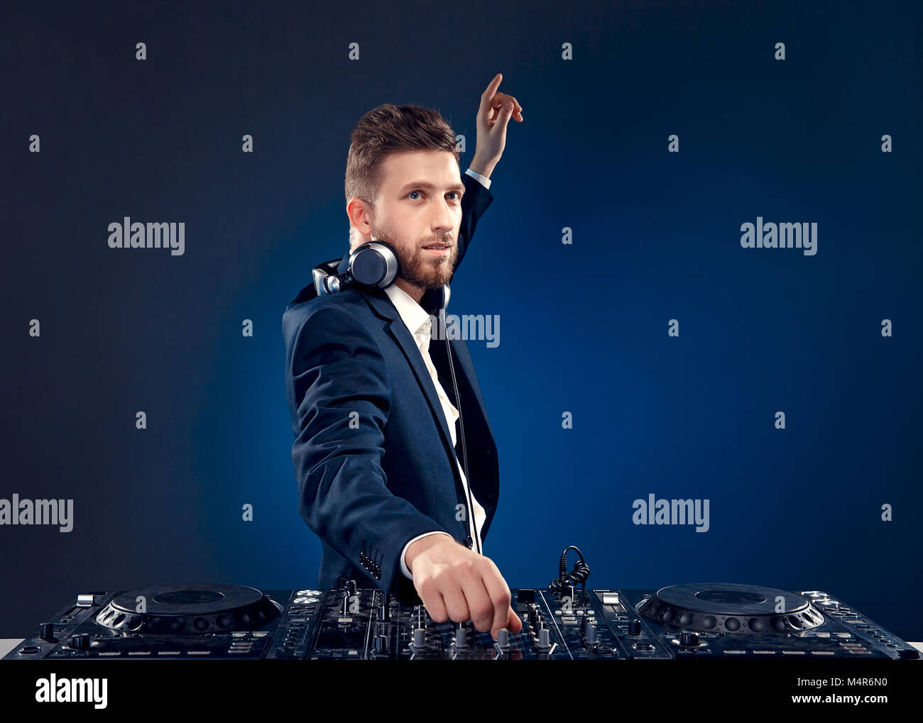 Closeup portrait of confident DJ with stylish hair style and headphones on neck mixing music on mixer while standing isolated on dark colored blue, cyan background Stock Photo - Alamy Closeup portrait of confident DJ with stylish hair style and headphones on neck mixing music on mixer while standing isolated on dark colored blue, cyan background Stock Photo - Alamy