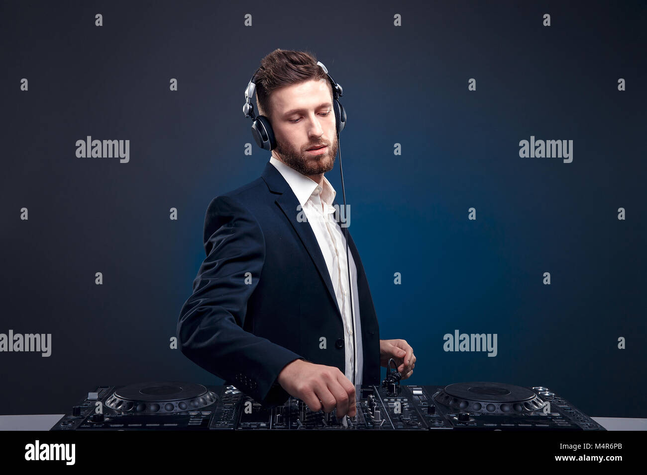 Closeup portrait of confident DJ with stylish hair style and headphones on  neck mixing music on mixer while standing isolated on dark colored blue,  cyan background Stock Photo - Alamy