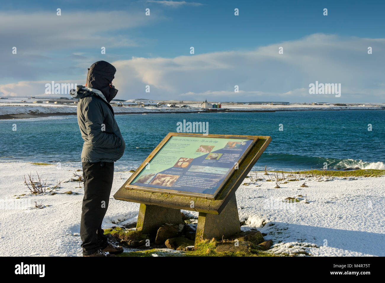 A man standing next to an information sign at the Ness of Duncansby, between John o'Groats and Duncansby Head, Caithness, Scotland, UK Stock Photo