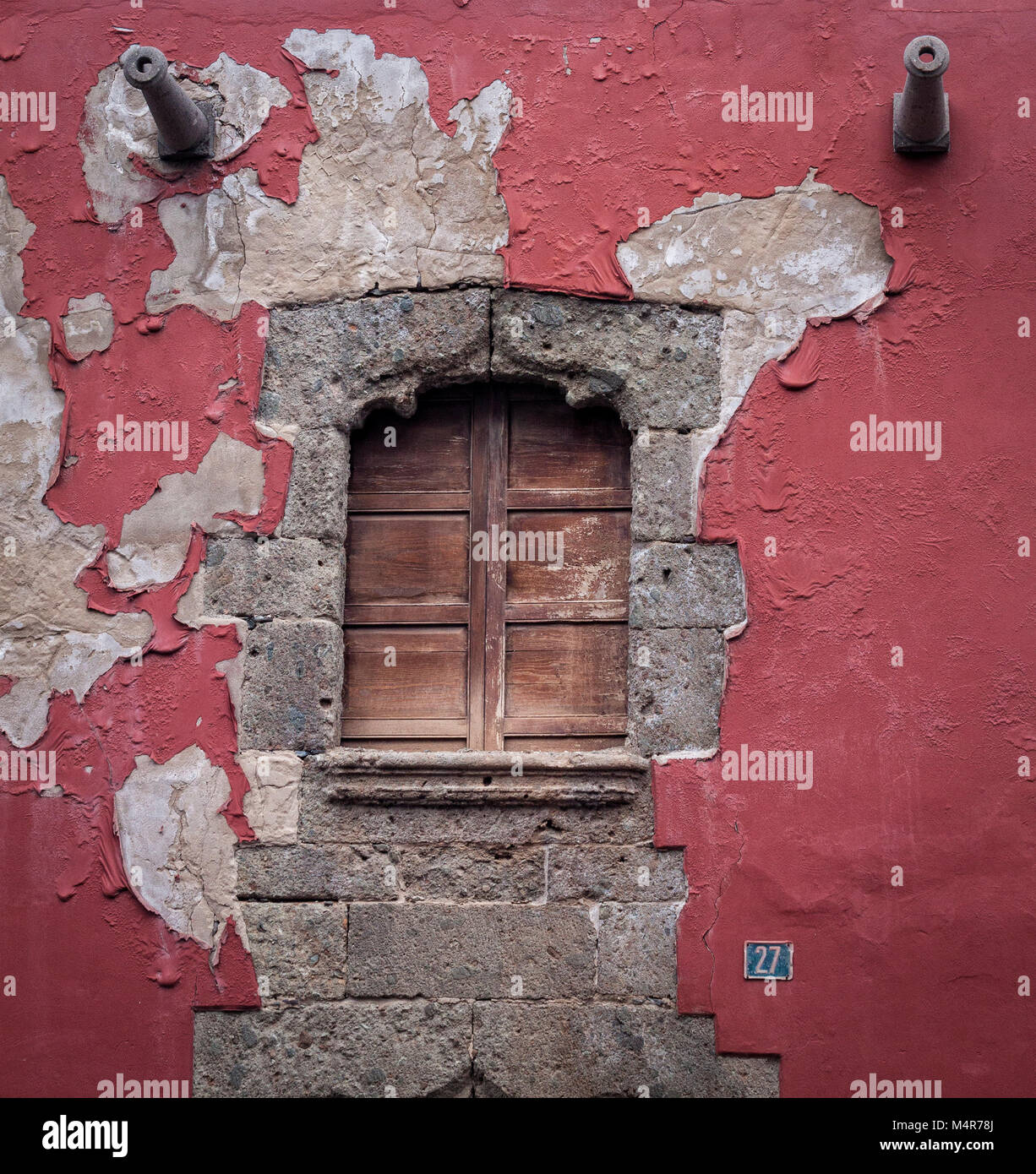 Spanish colonial wooden shutter window on the weathered red facade in