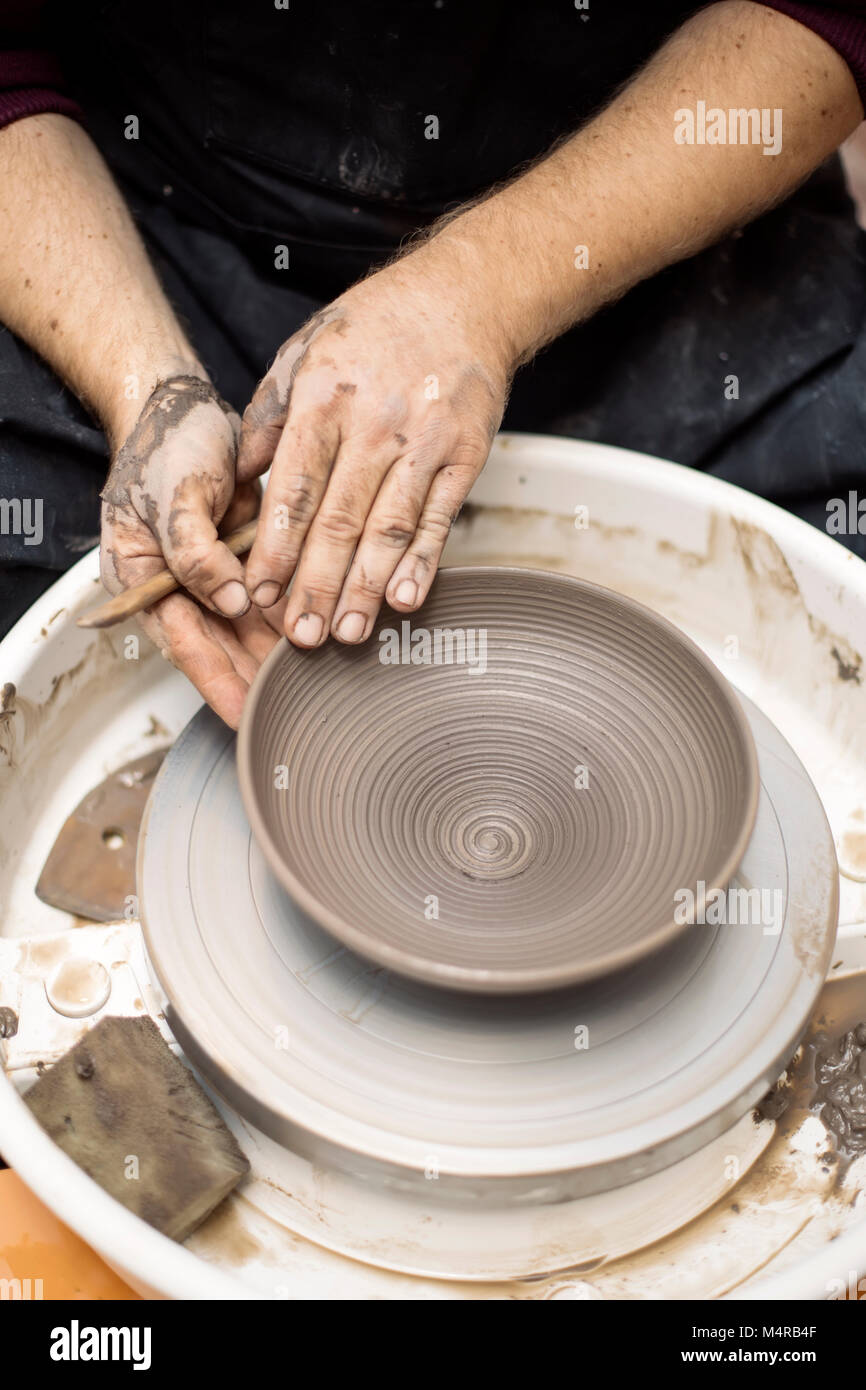 Close up detail view at an artist makes clay pottery on a spin wheel