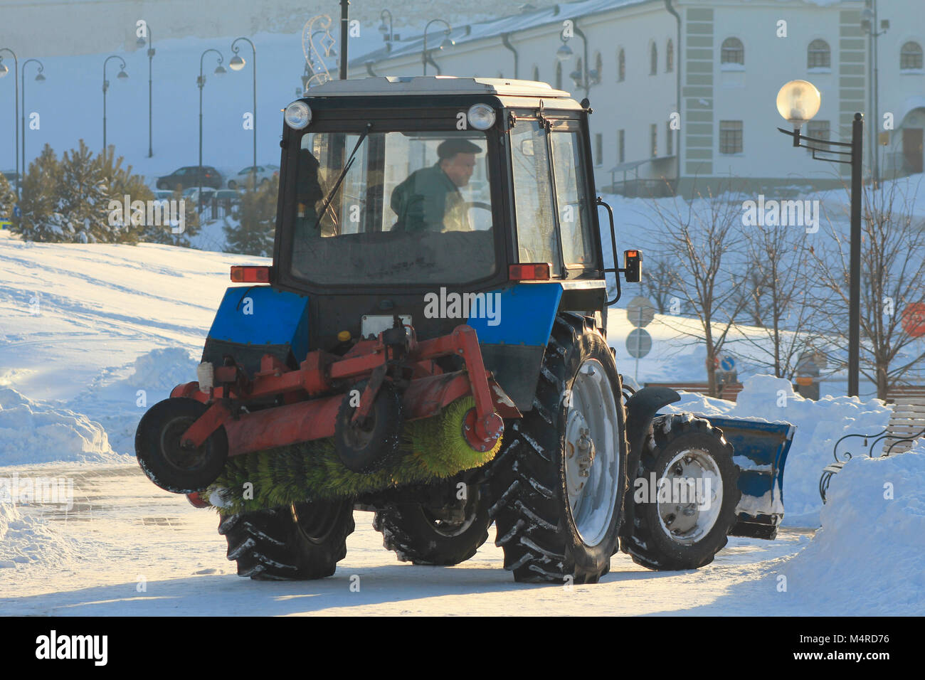 Clearing snow from the road with tractor in the city in winter Stock