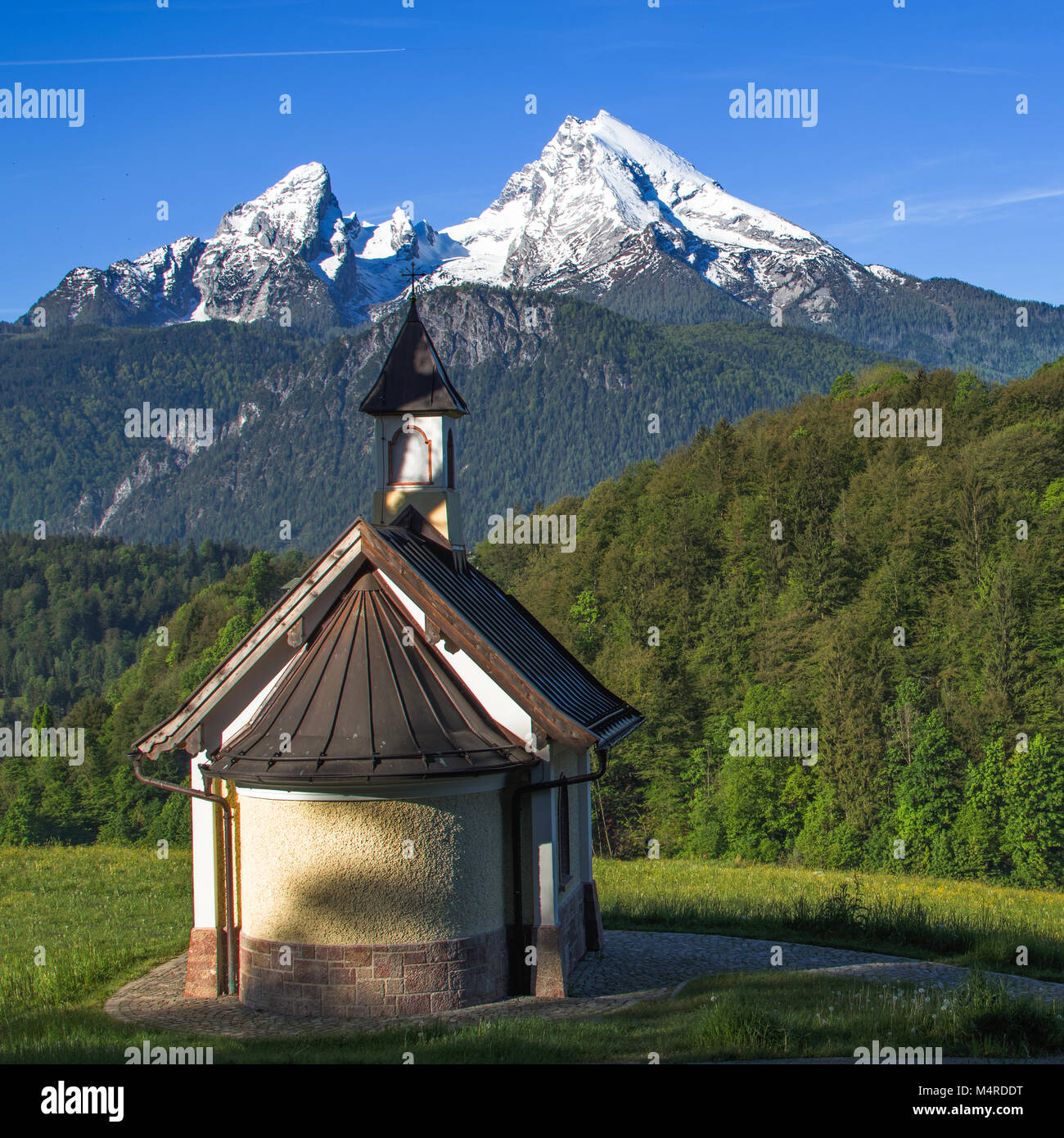 Small chapel Kirchleitn and snow-capped summits of Watzmann mountain. Square stock photo captured in German national park Berchtesgaden. Stock Photo