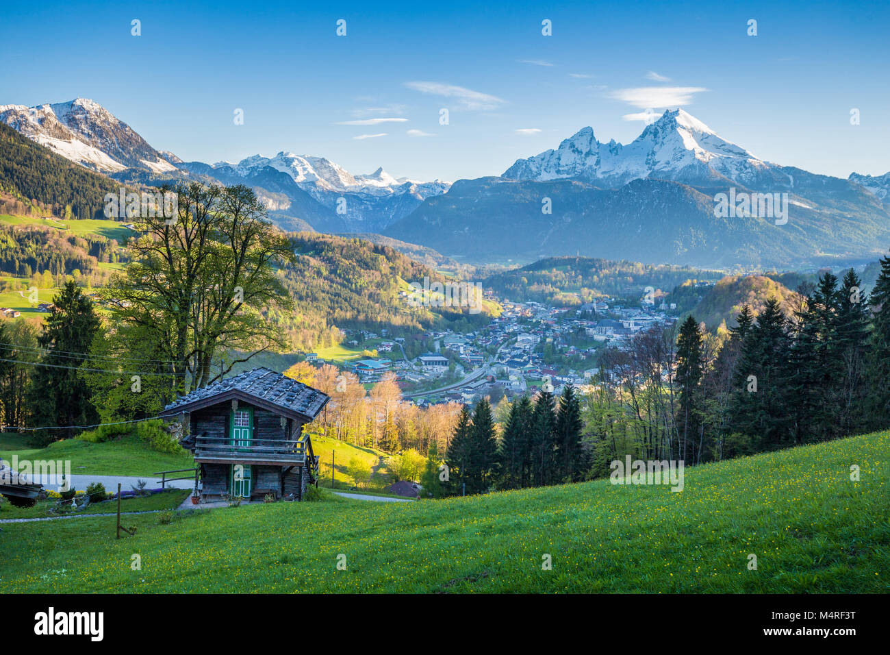 Beautiful view of idyllic alpine mountain scenery with traditional mountain cabin and snowcapped mountain peaks in scenic last evening light in summer Stock Photo