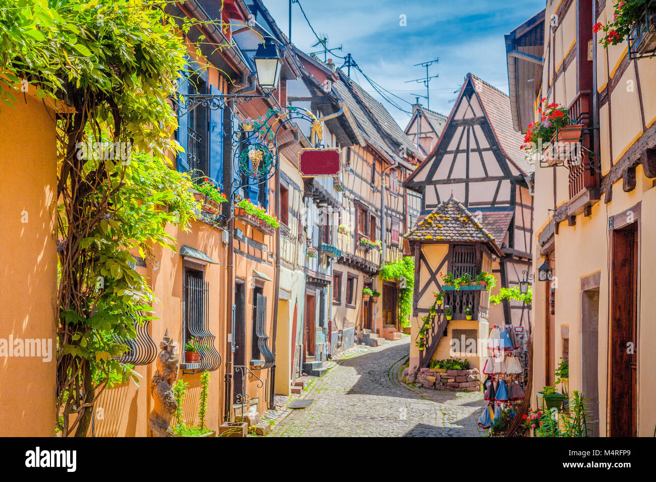 Charming street scene with colorful houses in the historic town of Eguisheim on a beautiful sunny day with blue sky in summer, Alsace, France Stock Photo