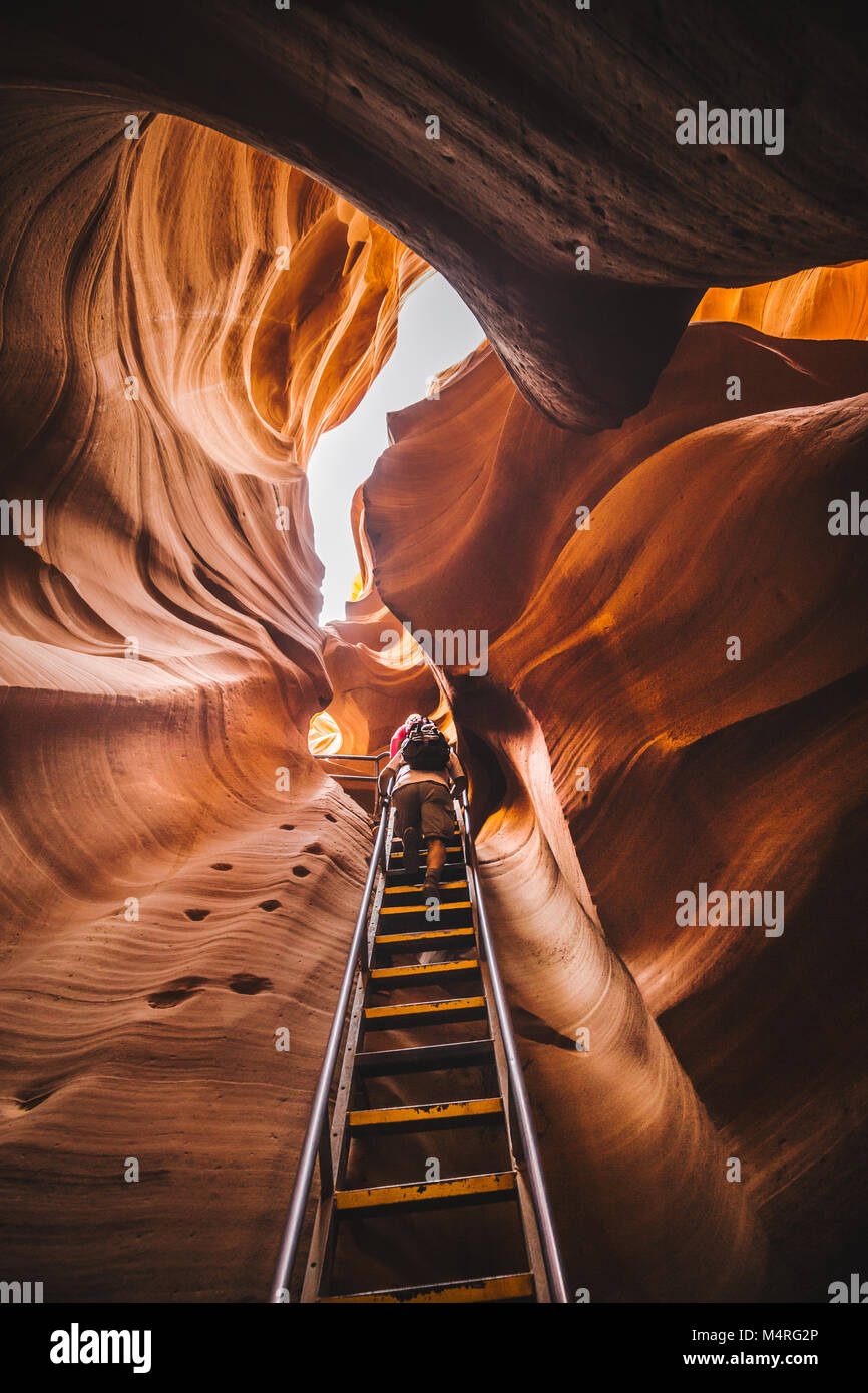 Amazing sandstone formations with hikers ascending a steep ladder in famous Antelope Canyon on a sunny day near the old town of Page at Lake Powell, A Stock Photo