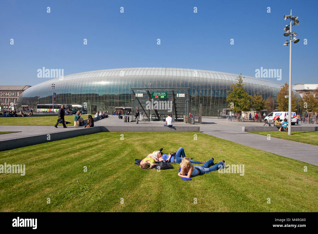 Youngsters on lawn in front of train station, modern glass construction covers the old building of 19th century, Strasbourg, Alsace, Bas-Rhin, France Stock Photo