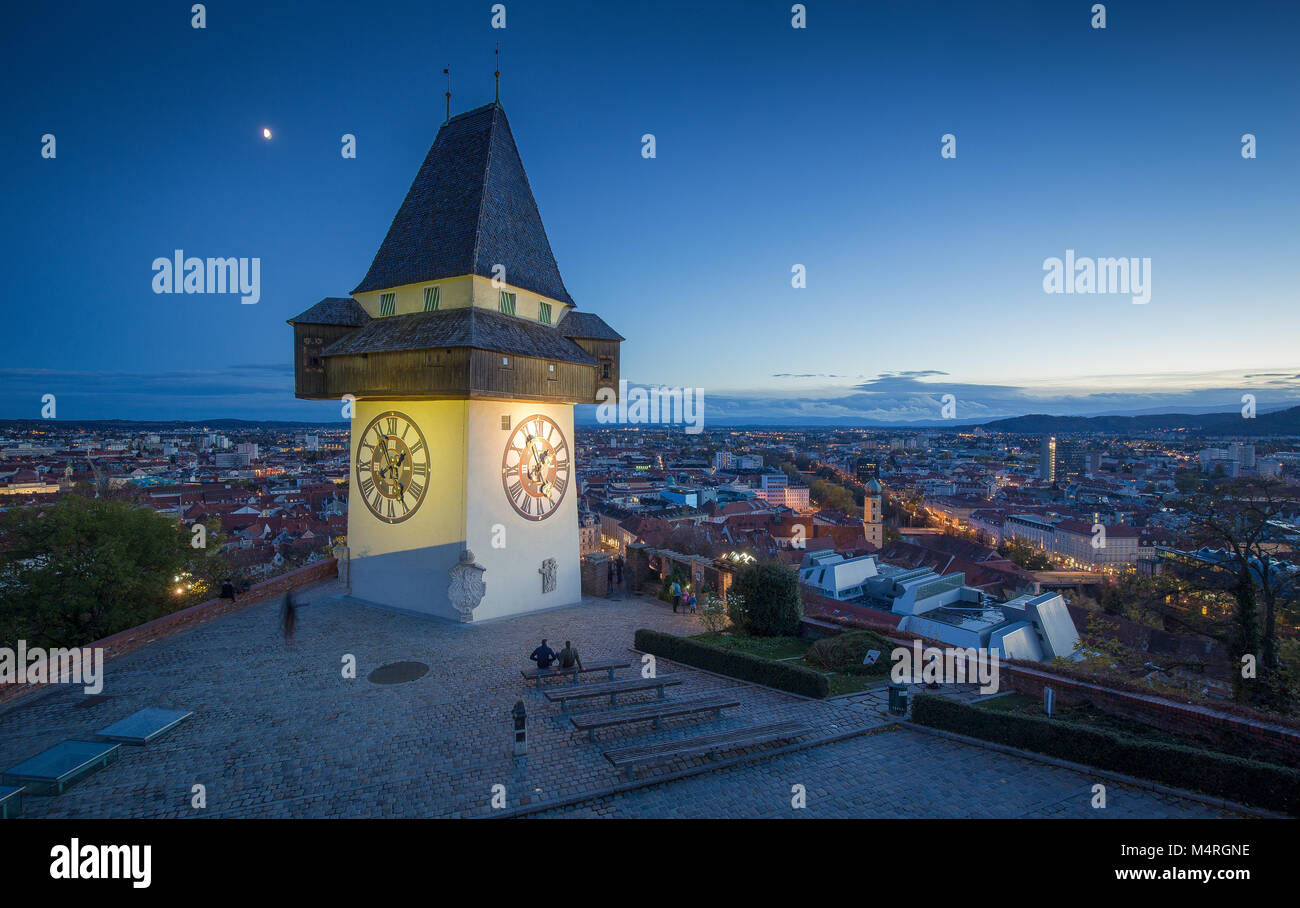 Panoramic aerial view of the old town of Graz with famous Grazer Uhrturm (clock tower) illuminated in beautiful evening twilight, Styria, Austria Stock Photo
