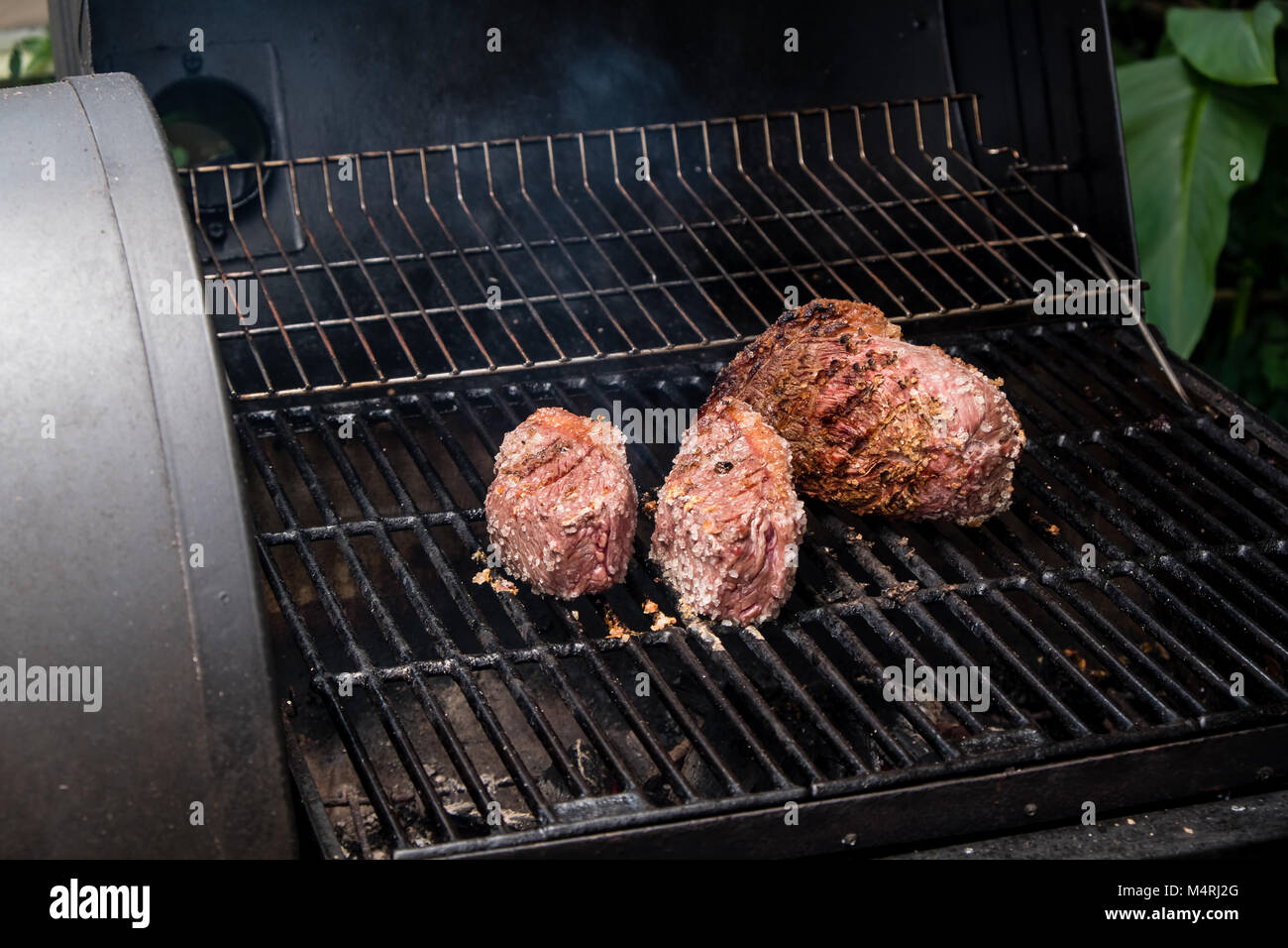 brazilian barbecue bbq on charcoal with three pieces of meat Stock