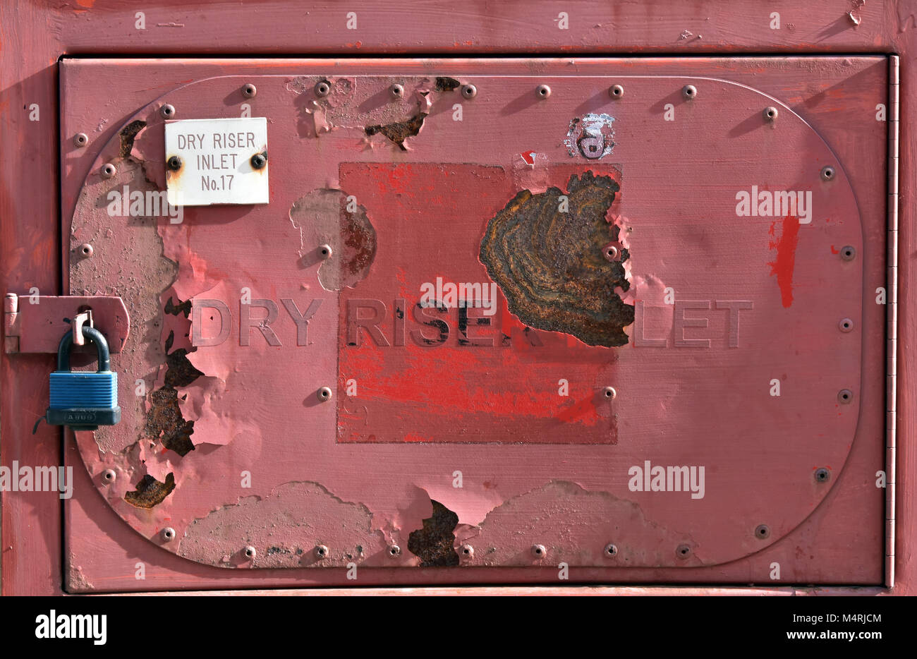 a rusty red painted flaky paintwork on a fire dry riser inlet outside ...