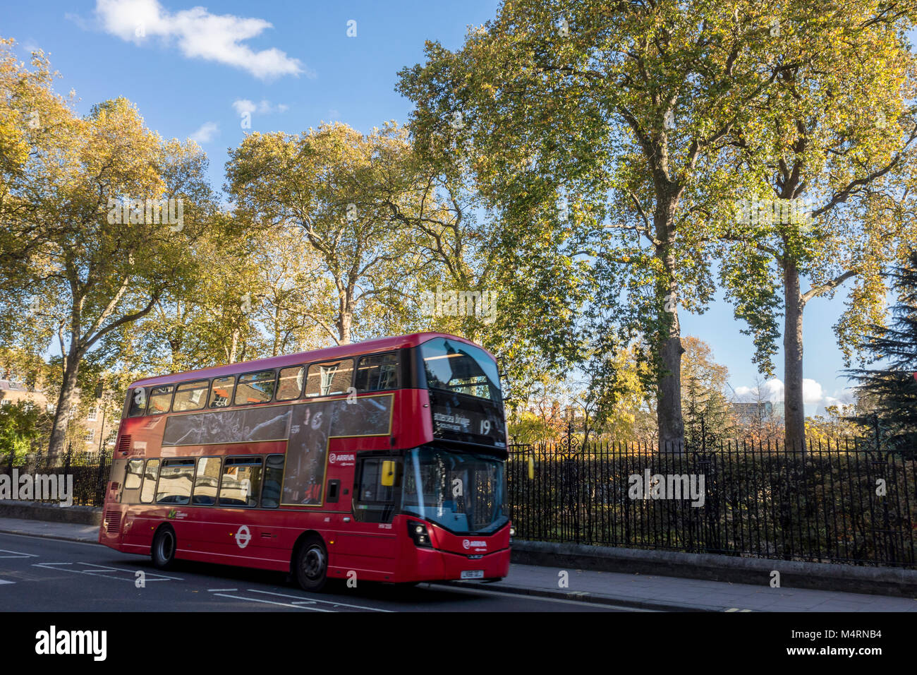 Red London bus on Theobalds Road in front of trees in Grays Inn Gardens, London, UK Stock Photo