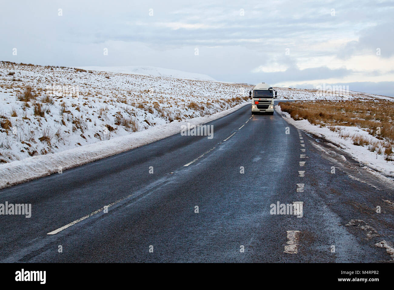 Brecon Beacons, UK: December 28, 2017: A Daf tanker truck drives on the A4059 in winter snow and ice conditions transporting Calor butane gas. Stock Photo