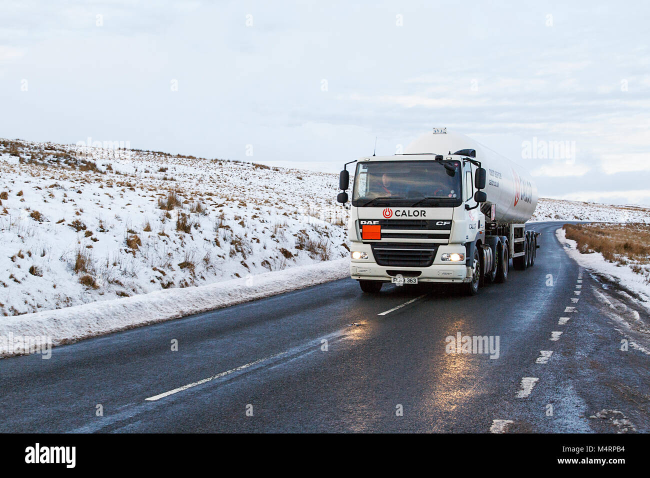 Brecon Beacons, UK: December 28, 2017: A Daf tanker truck drives on the A4059 in winter snow and ice conditions transporting Calor butane gas. Stock Photo