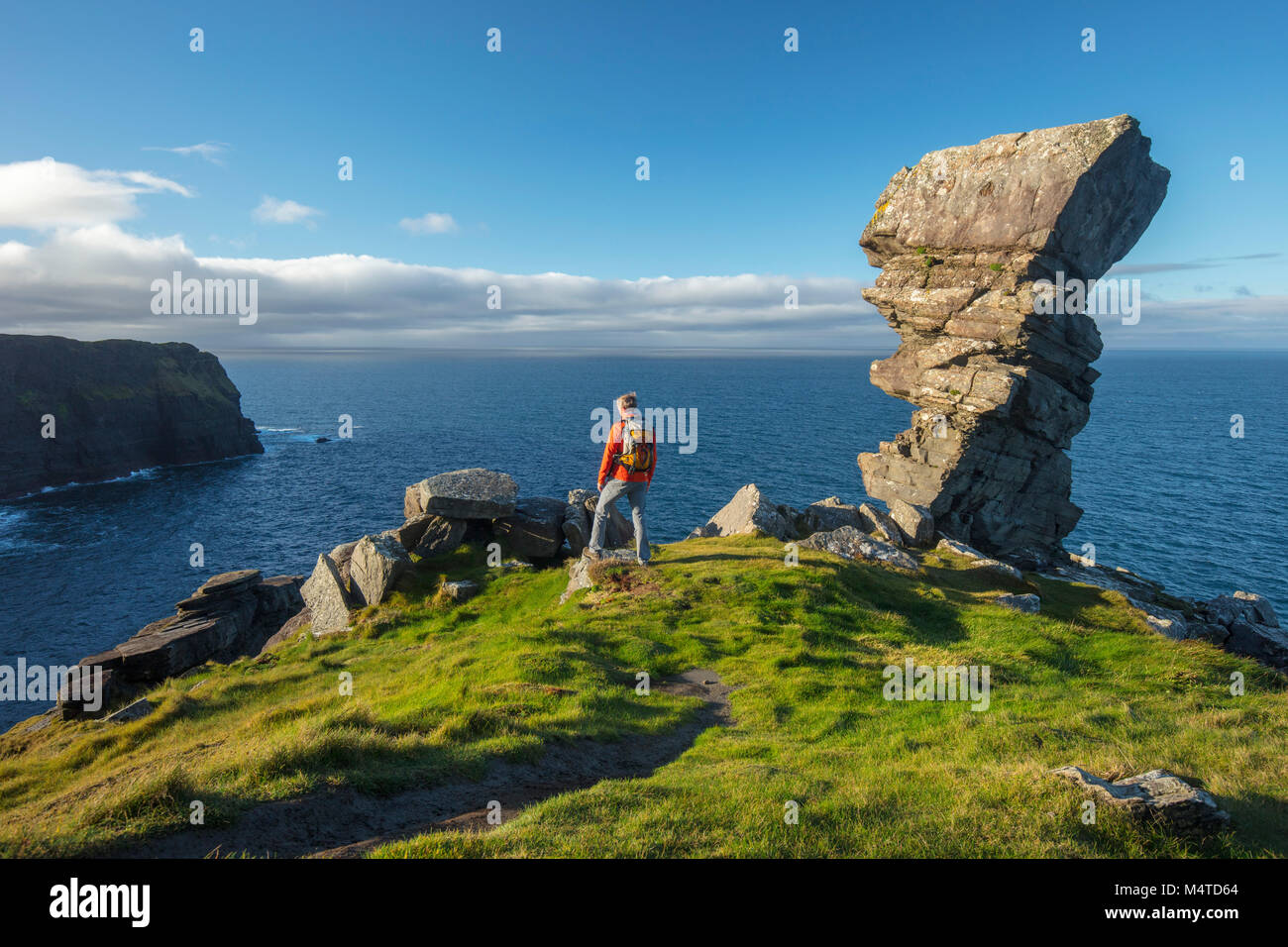 Hiker and rock formation at Hag's Head, Cliffs of Moher coastal walk, County Clare, Ireland. Stock Photo