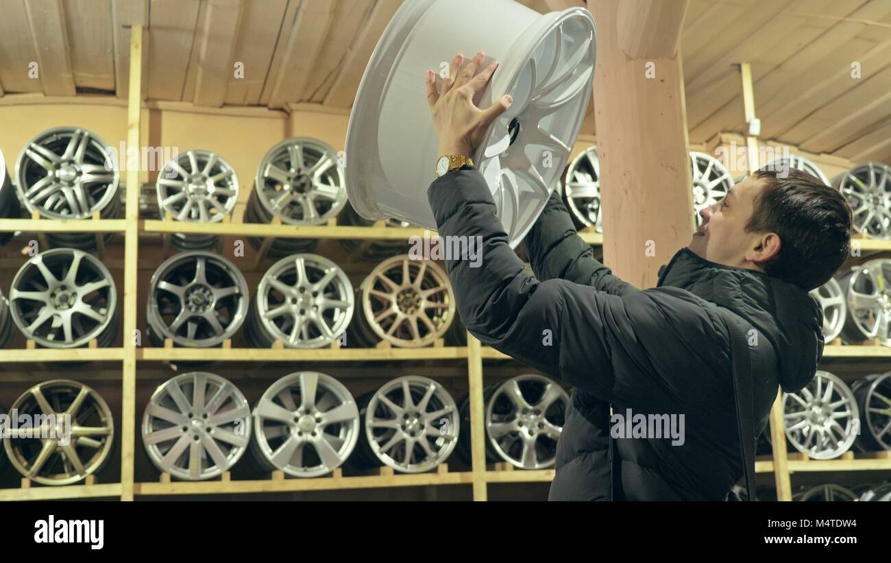 The man buys alloy wheels in his shop for his car. Stock Photo