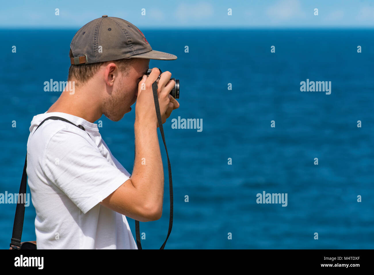 A young man taking photos near the ocean with an analogue SLR camera Stock Photo