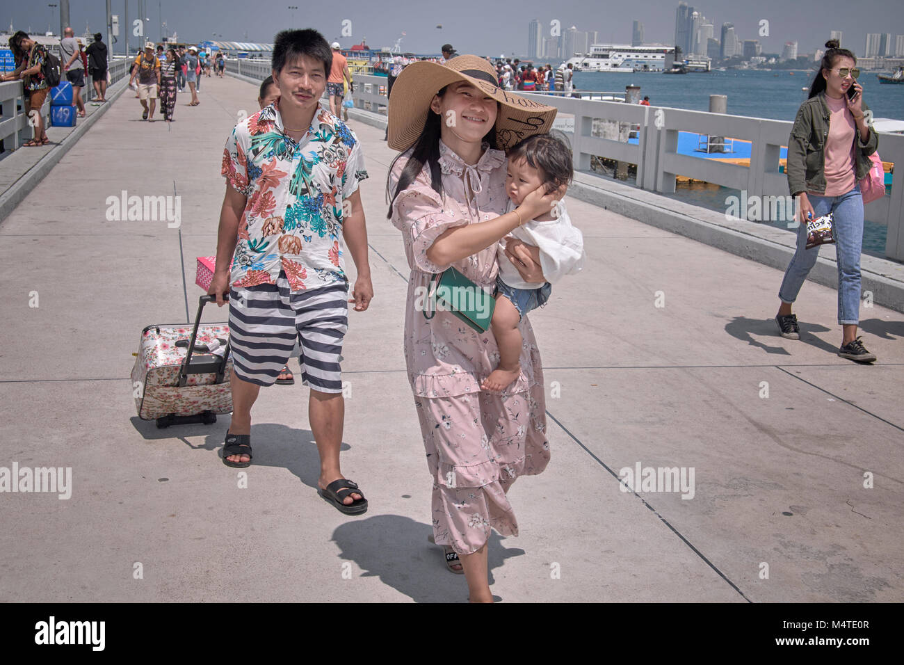 Young Asian day tripper family with mother carrying child in her arms. Woman child arms. Stock Photo