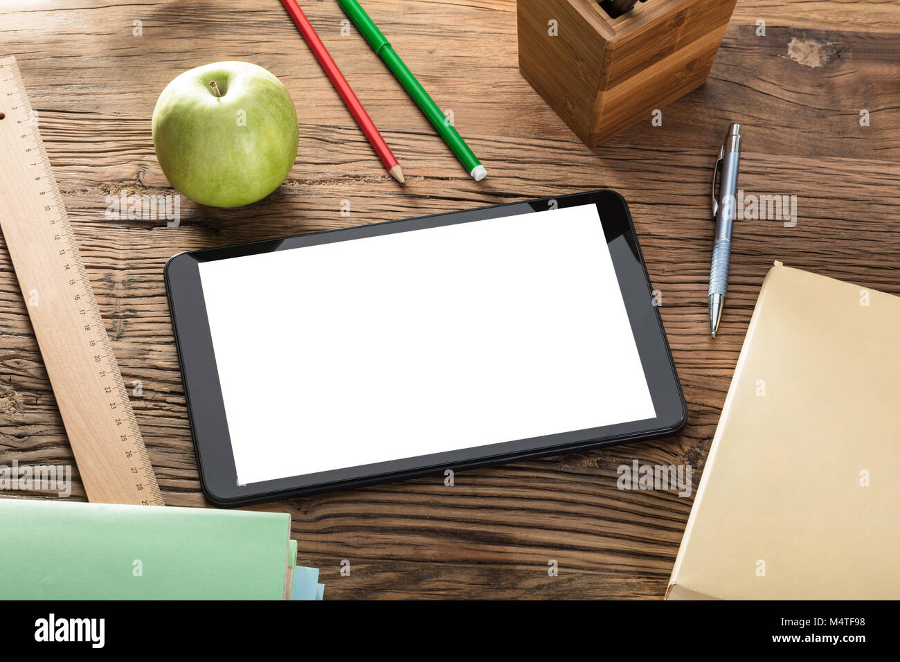 Green Apple And Blank Screen Digital Tablet On Wooden Table With Office Supplies Stock Photo