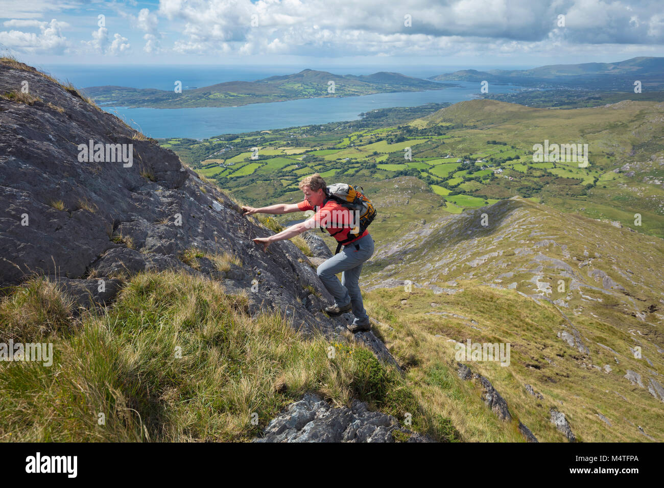 Hiker scrambling on the southwest ridge of Hungry Hill, Beara Peninsula, County Cork, Ireland. Stock Photo
