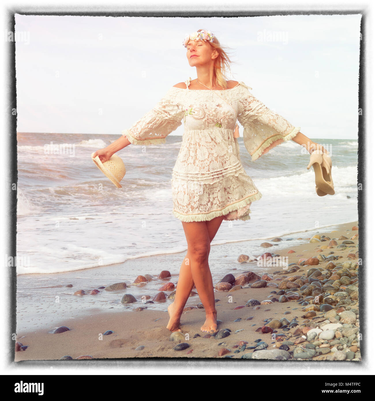 beautiful blond woman in white dress walking barefoot on the beach ...