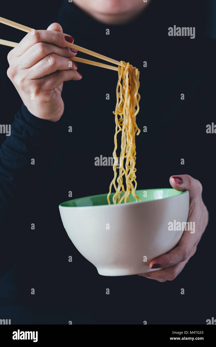 Woman holds a bowl of noodles with chopsticks Stock Photo