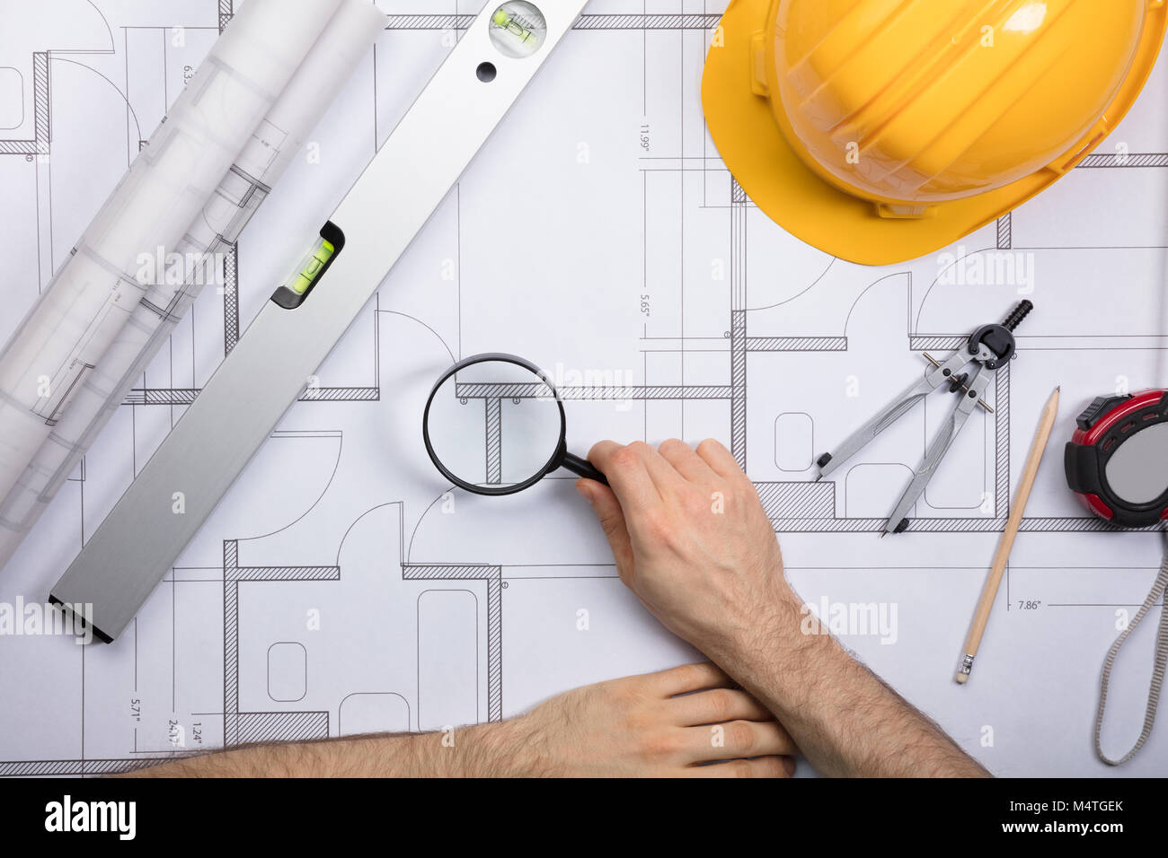 Close-up Of An Engineer Examining The Architectural Blueprint With Magnifying Glass At Workplace Stock Photo