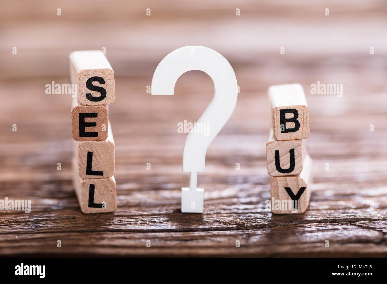 Close-up Of Buy Or Sell Option On Wooden Block With White Question Mark Sign Stock Photo