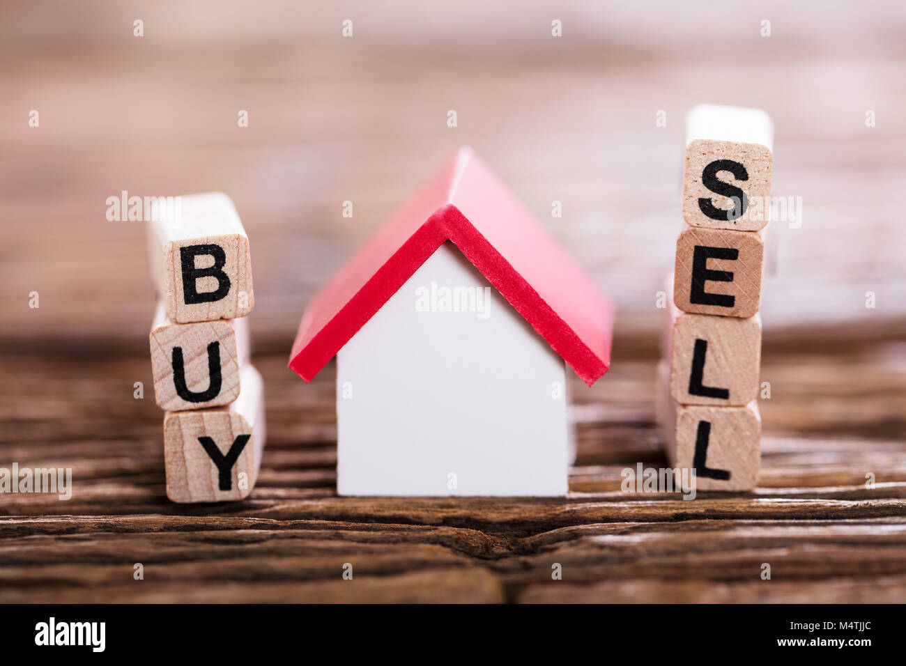 Close-up Of Buy Or Sell Option On Wooden Block With Small House Model Stock Photo
