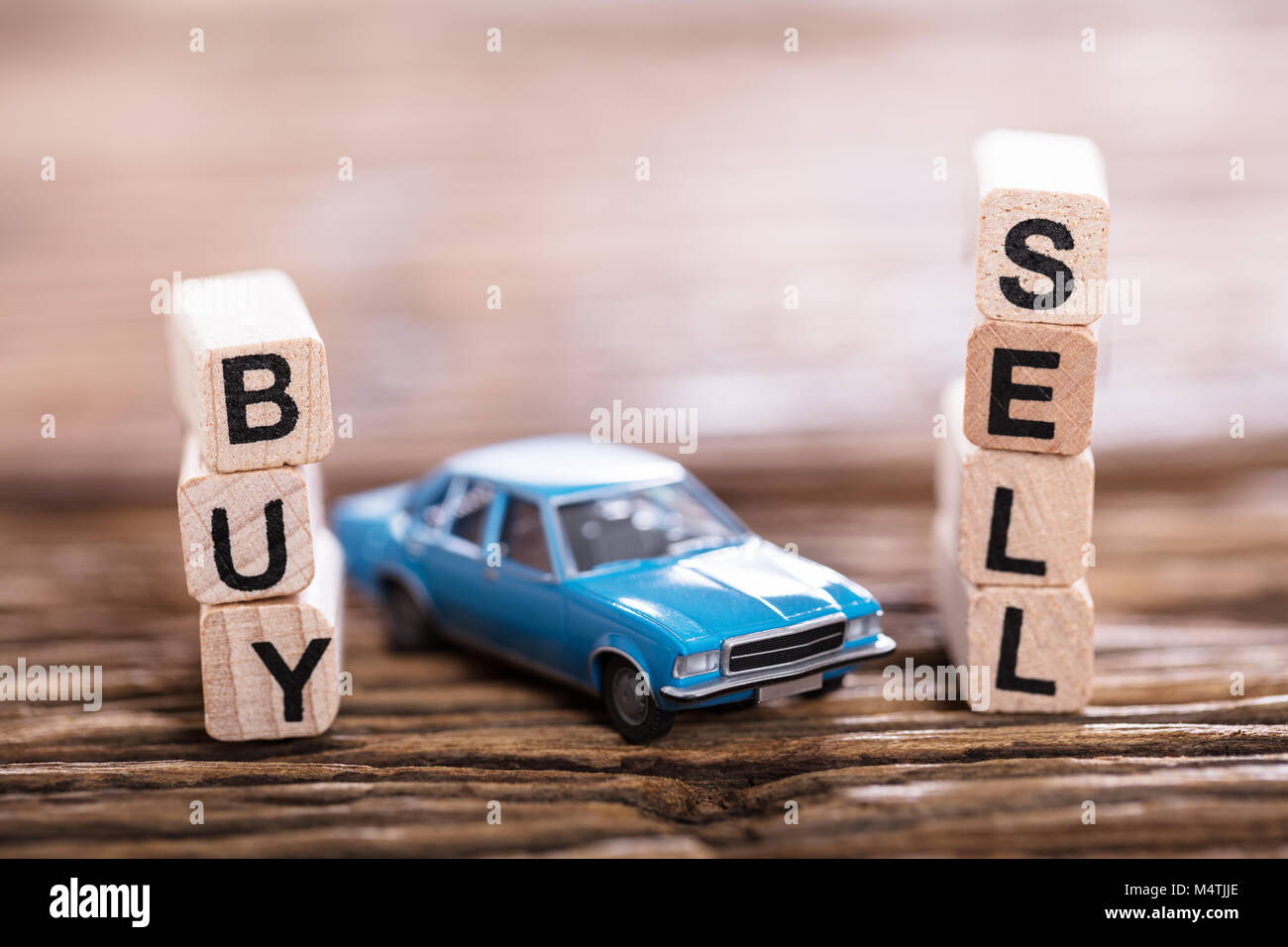 Close-up Of Buy Or Sell Option On Wooden Block With Small Blue Car Stock Photo