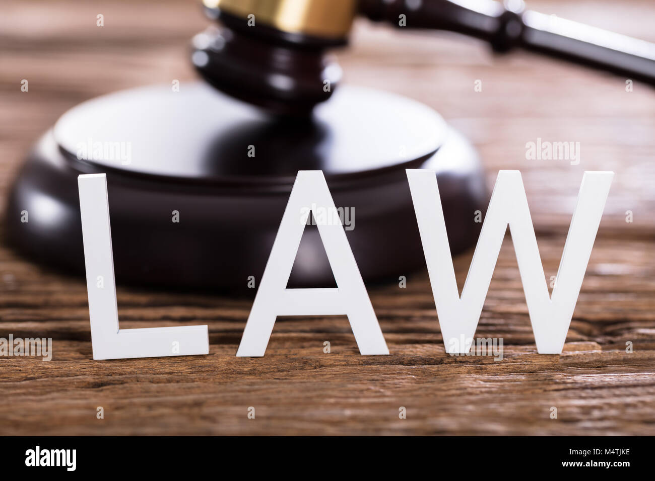 Close-up Of A Law Text In Front Of Gavel On Wooden Desk Stock Photo