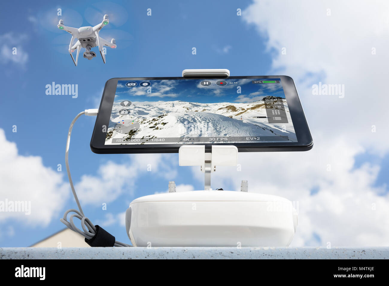 Low angle view of drone filming mountains seen on tablet computer against cloudy sky Stock Photo