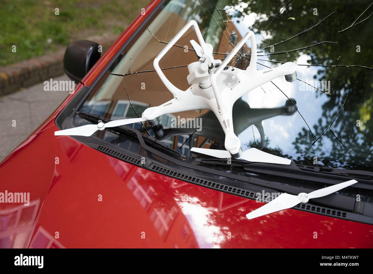 Closeup of damaged white drone on broken car windshield Stock Photo