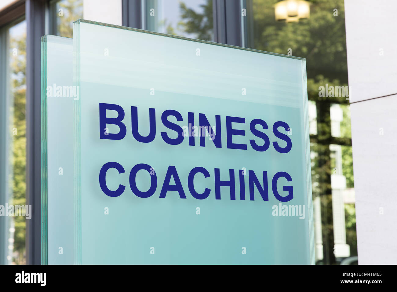 Closeup of business coaching sign on glass board outside building in city Stock Photo