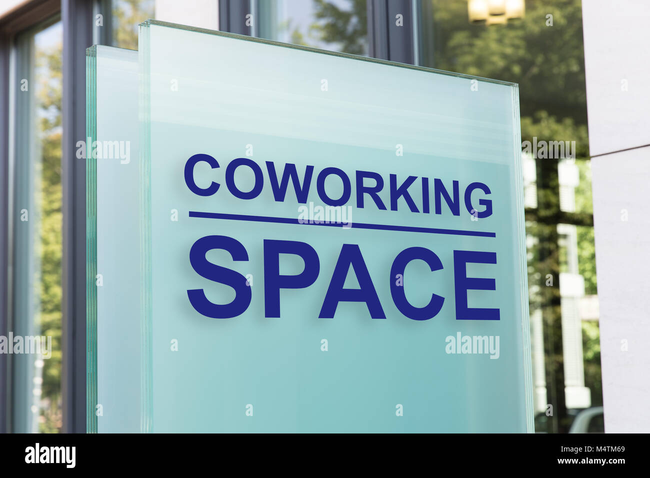 Closeup of coworking space sign on glass board outside building in city Stock Photo