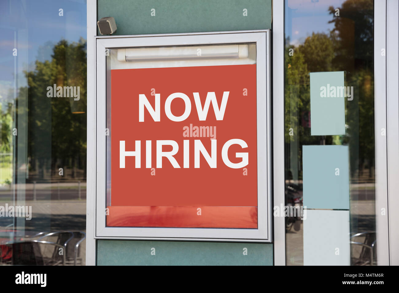 Closeup of now hiring sign outside modern office building Stock Photo