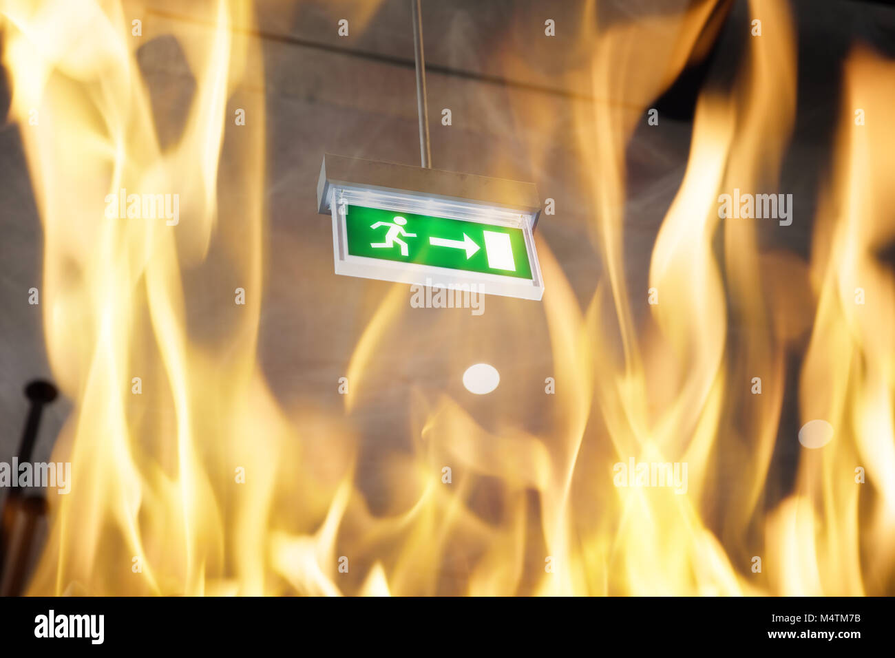 Low angle view of fire against emergency exit sign in building Stock Photo