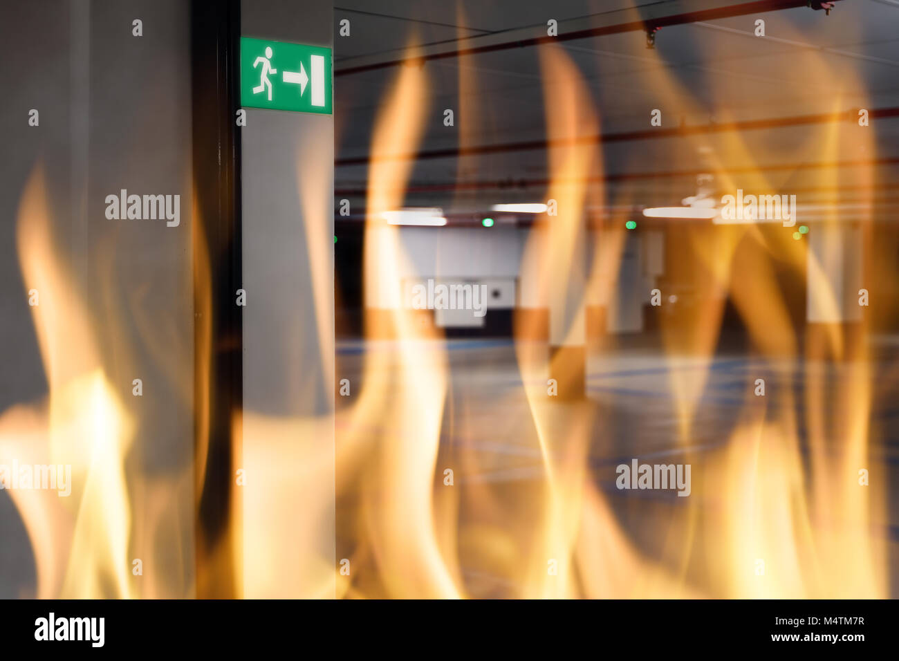 Fire against emergency exit sign at entrance of underground parking lot Stock Photo