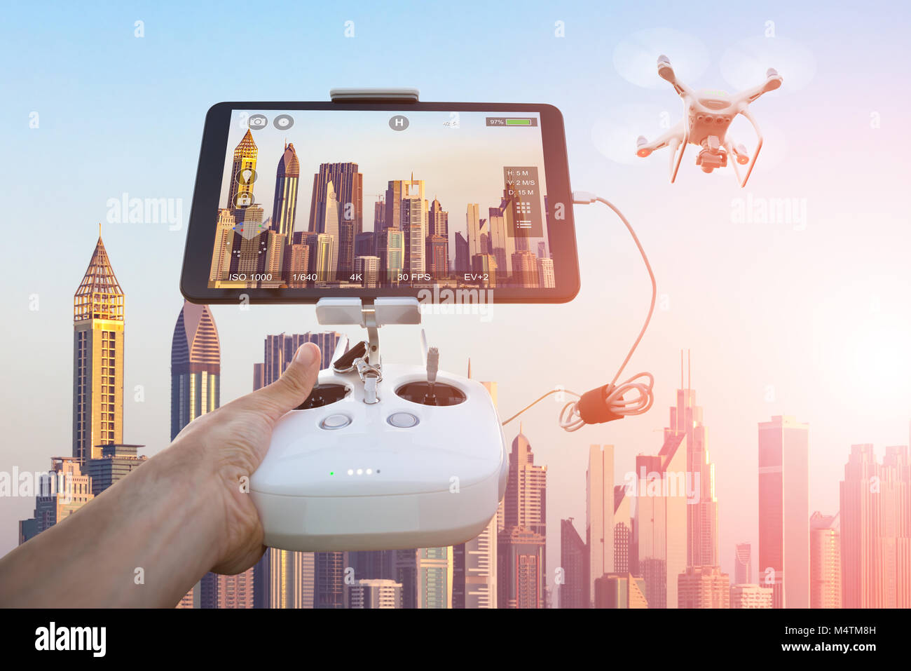 Cropped image of hand controlling drone filming cityscape seen on