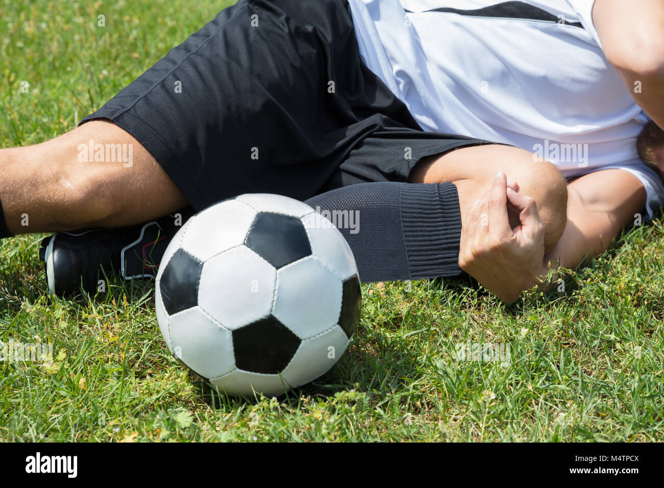 Closeup Of Male Soccer Player Suffering From Knee Injury Lying On