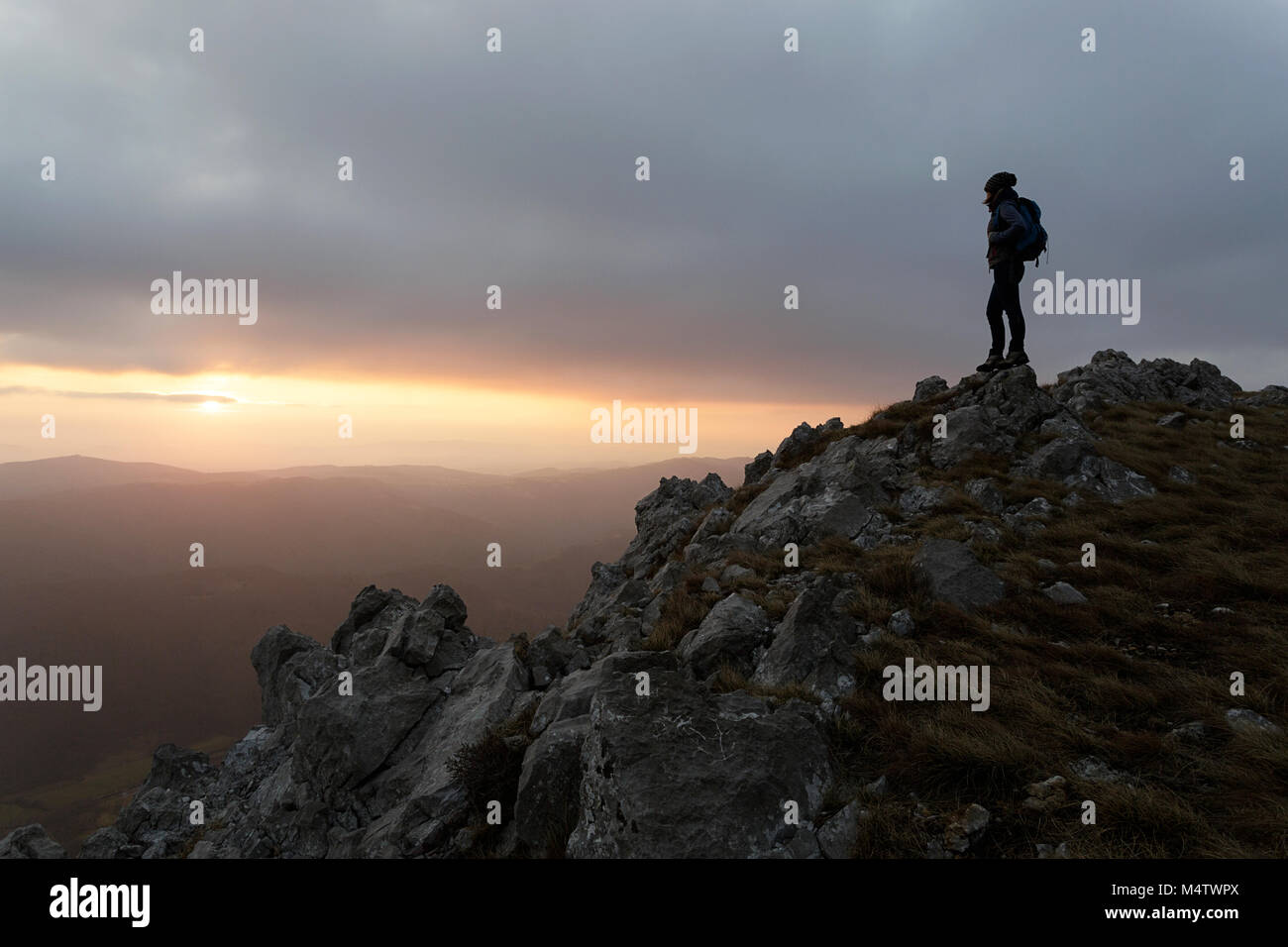 Silhouette of young woman standing on the top of the mountain with a ...