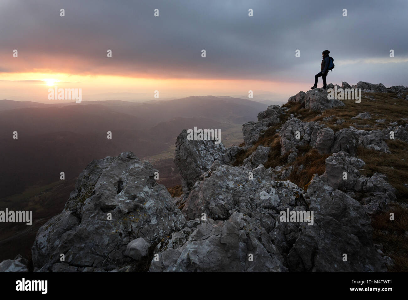 Silhouette of young woman standing on the top of the mountain with a ...