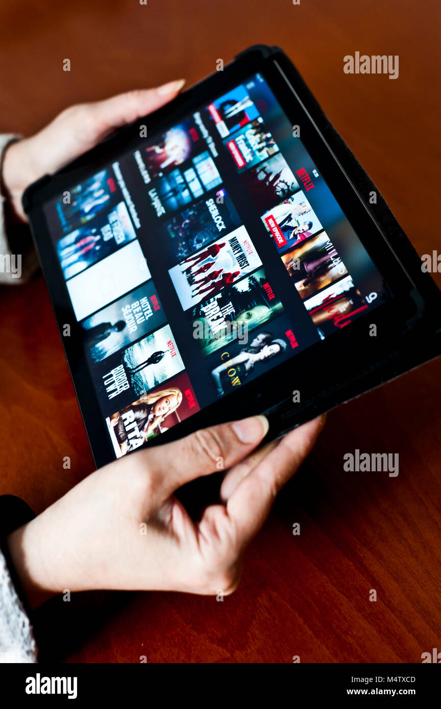 woman holding a tablet with Netflix screen on it Stock Photo