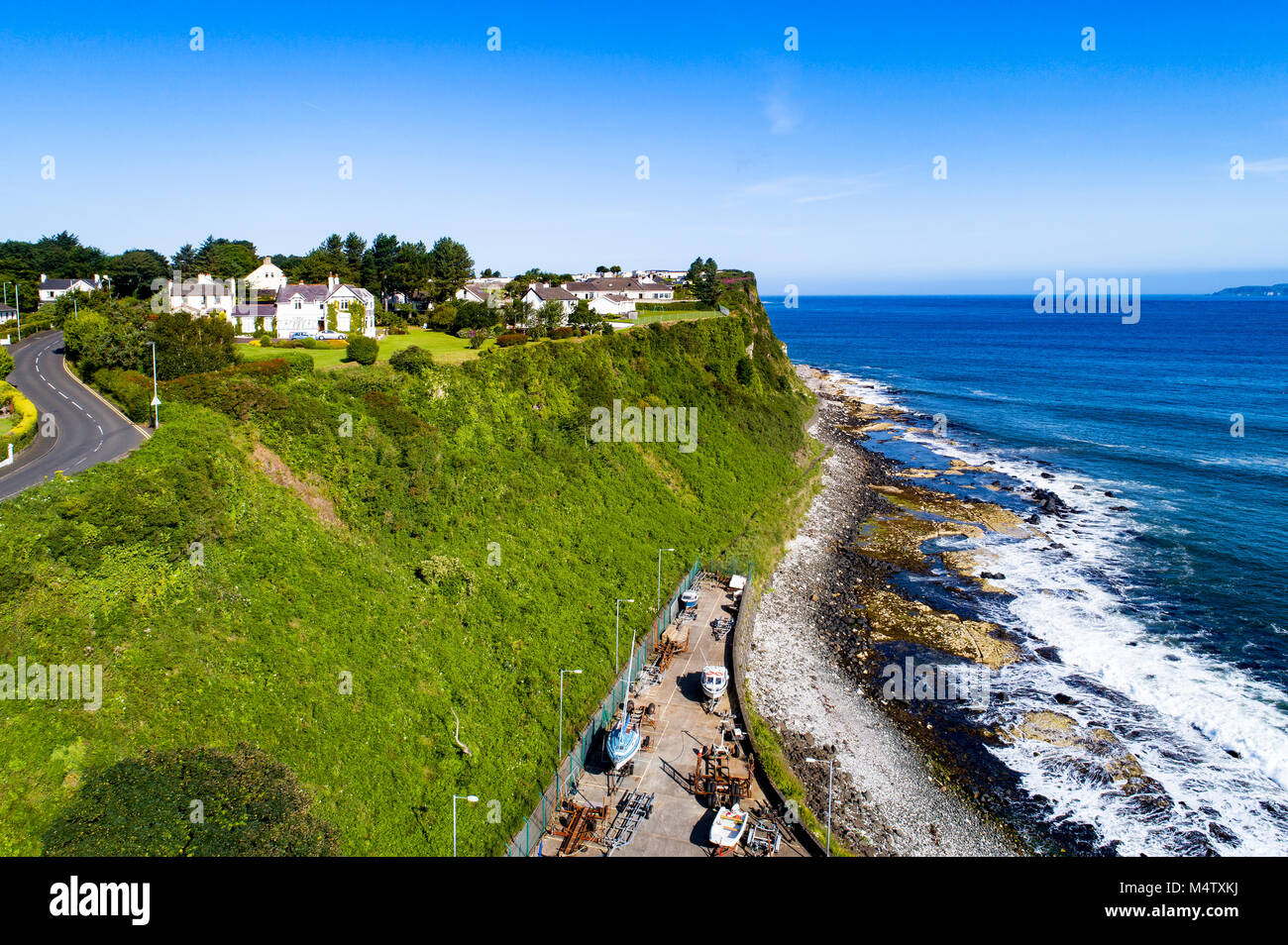 Atlantic coast with a steep cliff, marina and Causeway Coastal Road at Ballycastle, County Antrim, Northern Ireland, UK. Aerial view Stock Photo