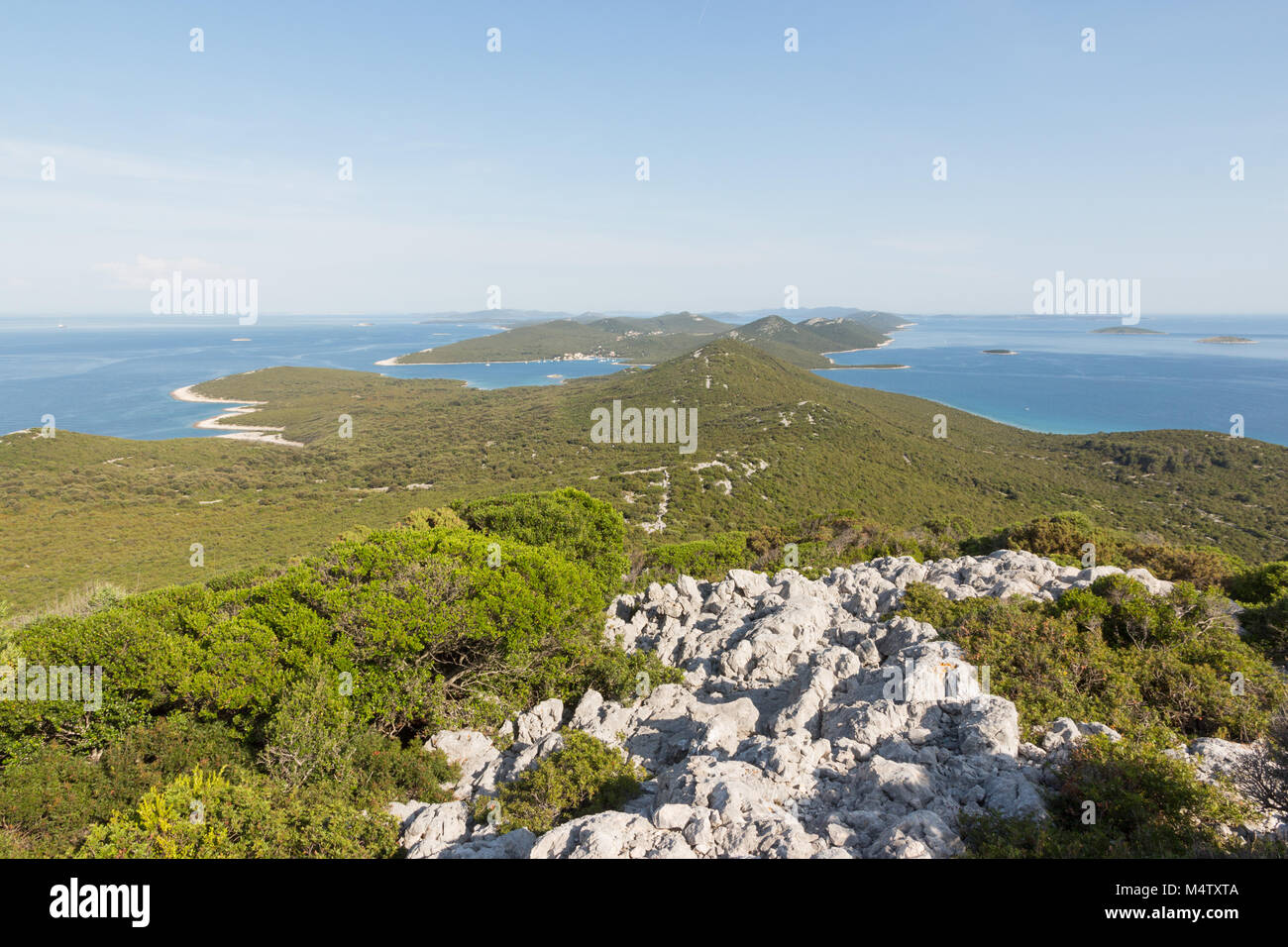View from forested hill onIst island towards Molat island with blue water and clear sky Stock Photo