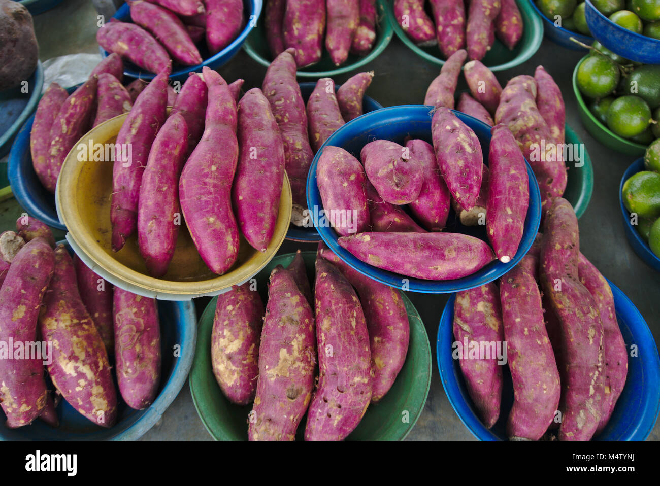 Red sweet potato and lime at a farmers market stall. Stock Photo