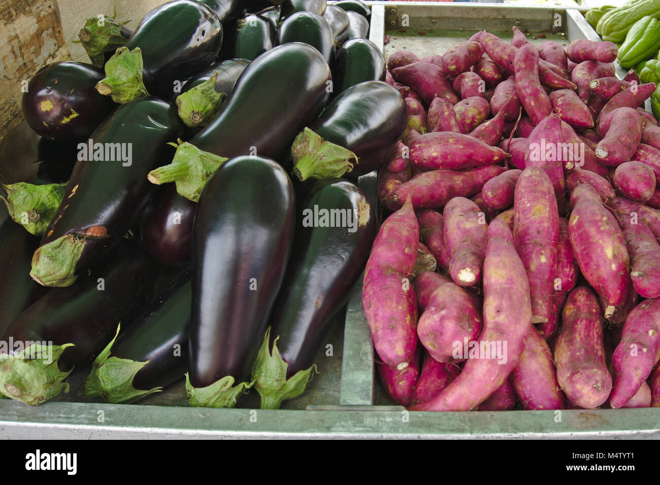 Red sweet potato and eggplant at a farmers market stall. Stock Photo