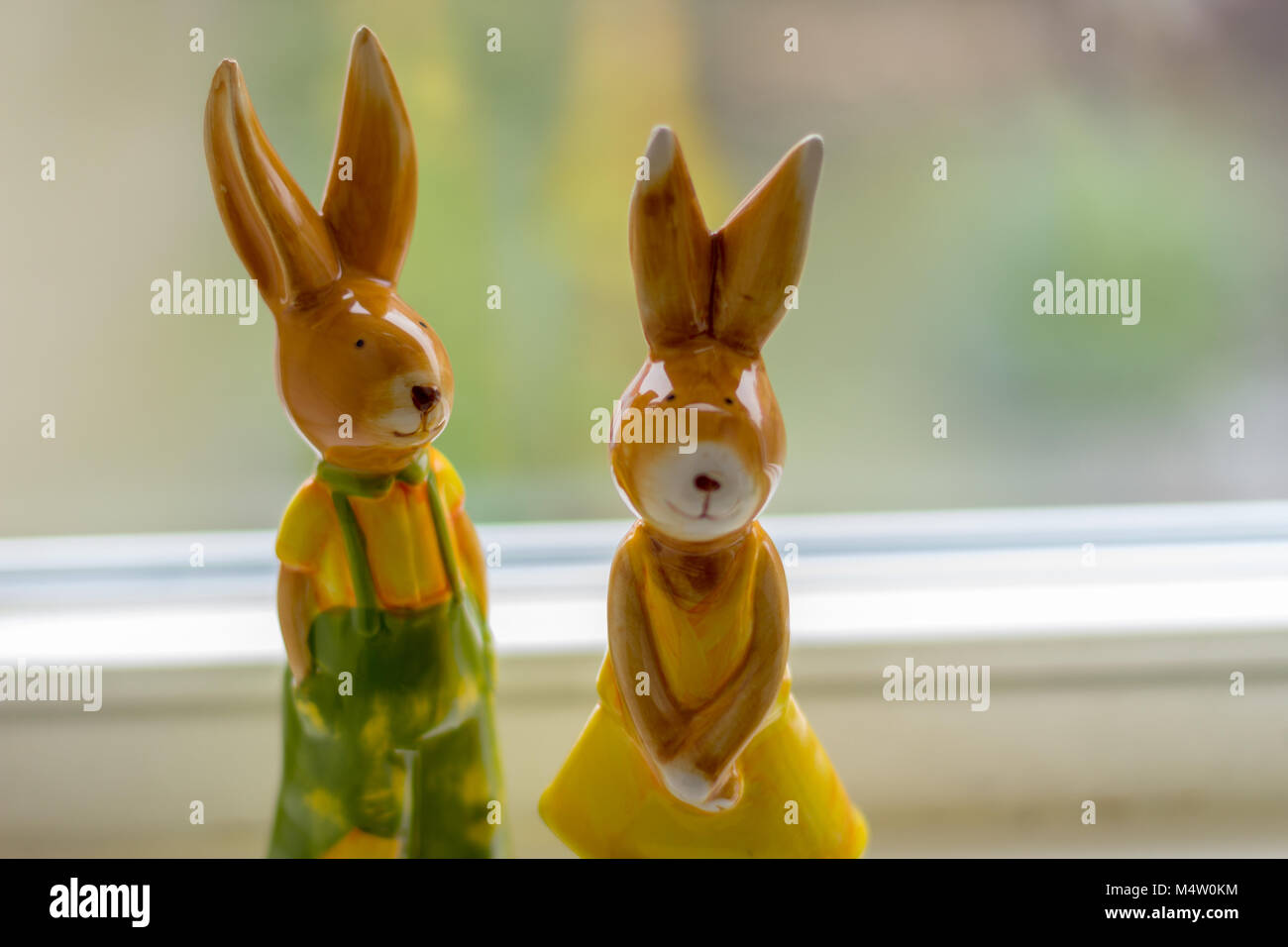 two decoration rabbits stand near a window Stock Photo - Alamy